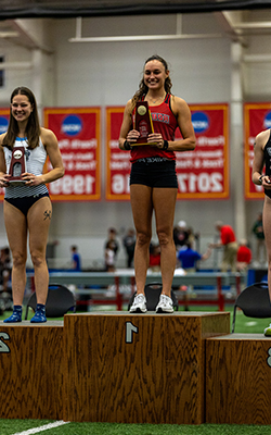 Brynn smiles while holding a trophy after winning the DII Pole Vault title